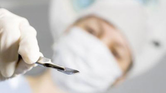 Doctor with scalpel hovering over patient